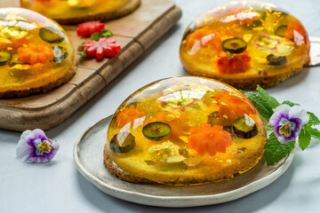 Lemon jelly globes with fresh fruit, edible flowers and gold flakes on pistachio biscuit - gourmet dessert