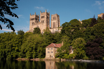 Obraz premium Durham England: 2022-06-07: Durham Cathedral exterior during sunny summer day. View from river wear with lush green trees