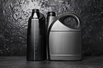 Motor oil in different canisters on black table near dark wall