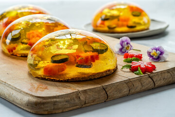 Lemon jelly globes with fresh fruit, edible flowers and gold flakes on pistachio biscuit - gourmet dessert