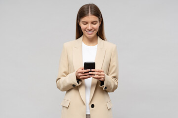 Woman CEO in jacket using phone to make appointment with partners, isolated on gray background