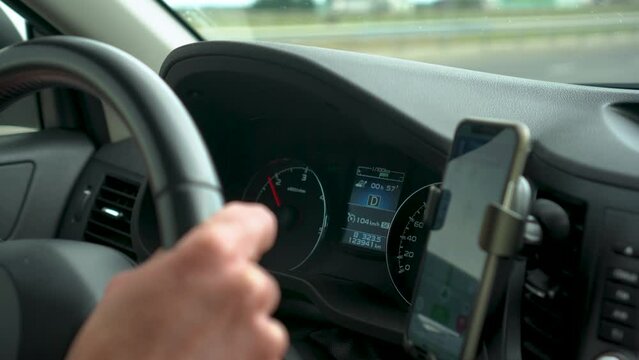 Hands on driving wheel and car dashboard with navigation gps on smartphone high speed drive
