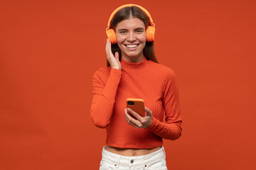 Portrait of woman listening to music in wireless headphones via popular music app on her phone