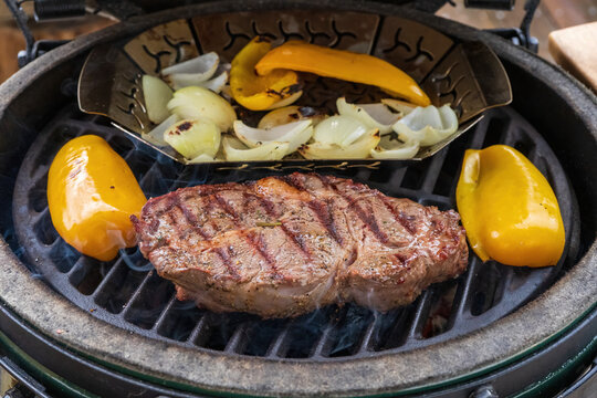 ready to eat - a grilled steak with yellow paprika, onions and rosemary from a outdoor charcoal grill 