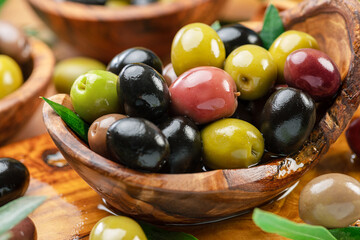 Kalamata, green and black olives in the wooden bowl. Food background.