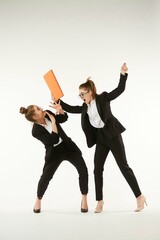 The conflict of two girls in office clothes. Boss and subordinate. Pure white background. The concept of business and corporate relationships in the enterprise.