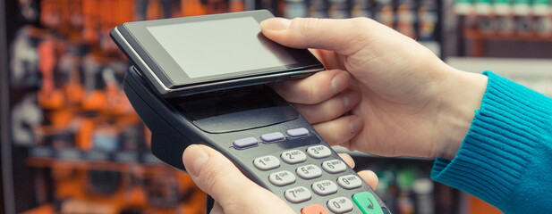 Payment terminal with mobile phone using for cashless paying for shopping in shop. Contactless...