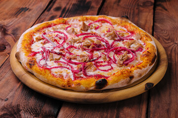 Pizza with tuna and red onion on wooden cutting board