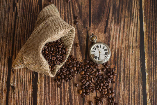 Pocket watch on table with coffee beans and jute sack