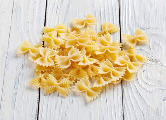 Heap of uncooked farfalle rigate pasta on white wooden background
