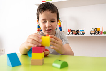 Fototapeta na wymiar Child playing with colourful educational toy blocks on the table at preschool or kindergarten. Kid having fun while engaged in creative learning and development
