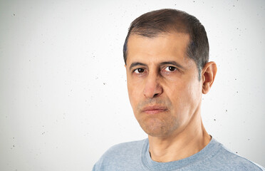 Portrait of an angry man looking at the camera with a concrete wall background