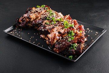 sliced BBQ pork ribs on black plate