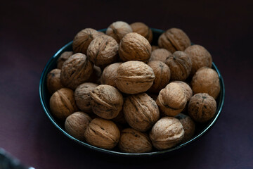 Bowl full of walnuts on black background with copy space