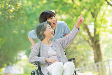 シニア女性の車椅子を押す女性医療従事者