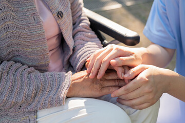 シニア女性の手を握る介護士の手元
