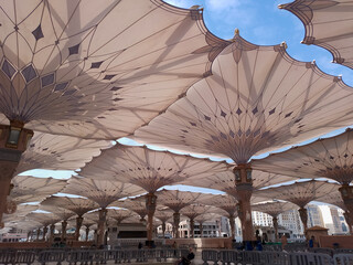 Medina, Saudi Arabia - October 07, 2022: Umbrella construction on the square of Al-Masjid An-Nabawi or Prophet Muhammed Mosque are protecting people from sun at daytime and work as lights at night