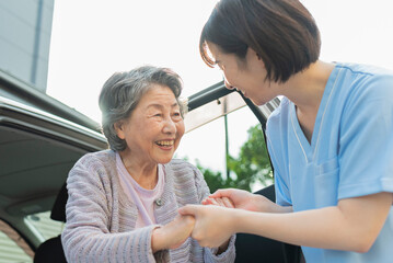 Fototapeta premium シニア女性が車から降りるのを手伝う女性ヘルパー