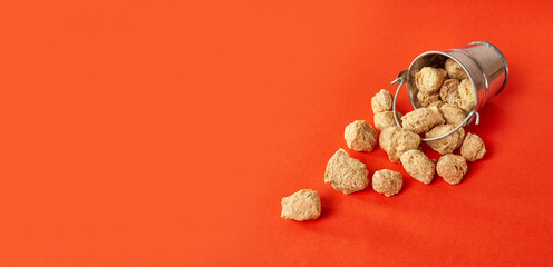 Textured pieces of soy flour in a small bucket on a red background.