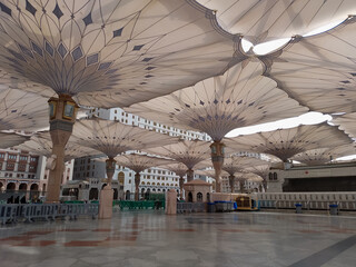 Medina, Saudi Arabia - October 07, 2022: Umbrella construction on the square of Al-Masjid An-Nabawi or Prophet Muhammed Mosque are protecting people from sun at daytime and work as lights at night