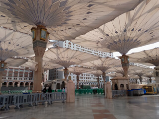 Medina, Saudi Arabia - October 07, 2022: Umbrella construction on the square of Al-Masjid An-Nabawi or Prophet Muhammed Mosque are protecting people from sun at daytime and work as lights at night