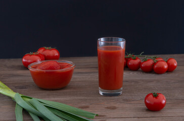 Glass with fresh tomato juice , garlic and tomatoes on a wooden background