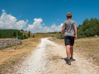 Young blond hair man in shorts and grey t shirt  walking on gravel road