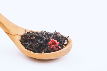 aromatic black dry tea with raspberries on a wooden spoon isolated on white background