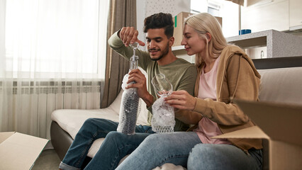 Girl with glass looking at man opening wine bottle