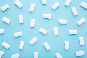 White chewing gum pads on light blue table. Pattern background. Pastel color. Closeup. Top down view.