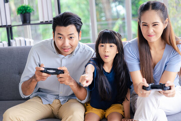 Young family mother father and daughter with joy stick enjoy playing playing video game online station game at home