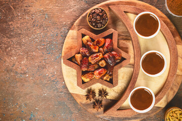 Turkish coffee cups placed with roasted coffee beans and fresh dates on rustic background. Top view with copy space.