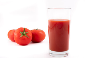 Tomato juice in a glass and ripe tomatoes on a white background