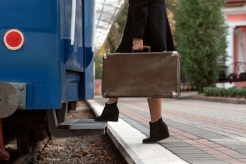 Girl in retro clothes with leather vintage suitcase travels in train. Woman traveler.