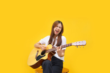Women are playing acoustic guitar and singing the song over isolated yellow background