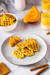 Belgian homemade pumpkin waffles on a plate on the table. Autumn baking. Vertical view