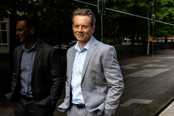 A handsome businessman in a grey suit in an urban city environment