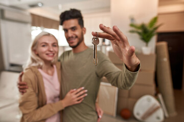 Obraz na płótnie Canvas Focus of keys in hand of man hug woman in new flat