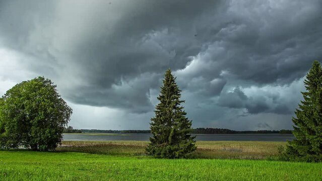 Time lapse of dense storm clouds moving together over a lake in the countryside.