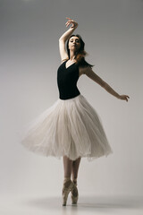 ballerina in a bodysuit and a white skirt improvises classical and modern choreography in a photo...