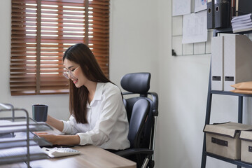 Business concept, Businesswoman is drinking coffee while reading business document in office