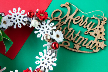 スノーフレークとポインセチアとクリスマスボールのクリスマスリースとメリークリスマスの飾り（緑と赤の背景）