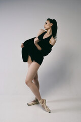 ballerina in a bodysuit and a black jacket improvises classical and modern choreography in a photo...