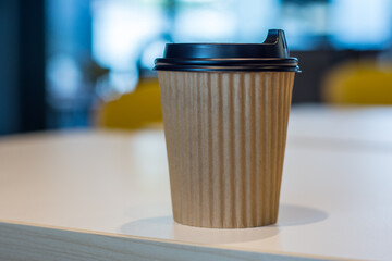 hot coffee in brown paper cup, coffee in white desk, Takeaway coffee in cafe shop, on blur background