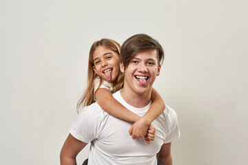 Boy hold sister piggyback and stick out tongues