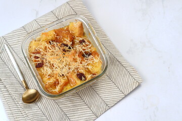 Homemade bread butter pudding with raisins and grated cheese as topping