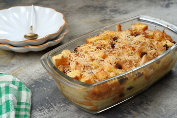 Homemade bread butter pudding with raisins and grated cheese as topping