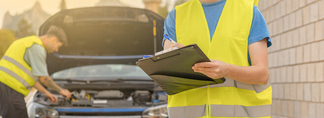Dos técnicos revisando el coche en una avería en la carretera.
