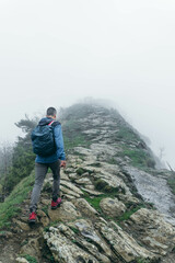 Alone man with equipment in the nature with several fog hiking the mountain