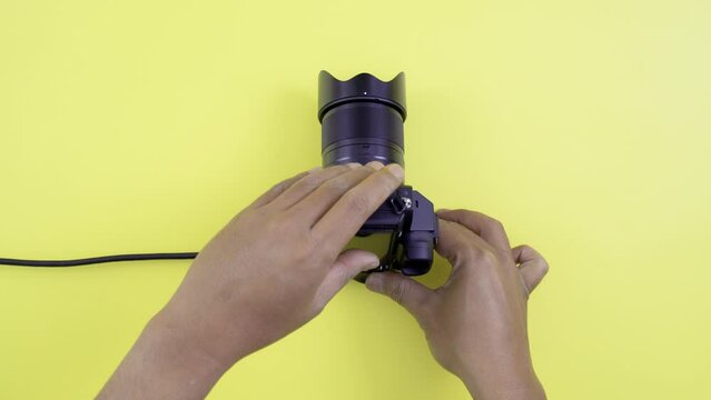 Closeup footage man hand inserting HDMI converter to mini HDMI then attaching to mirrorless camera on yellow background